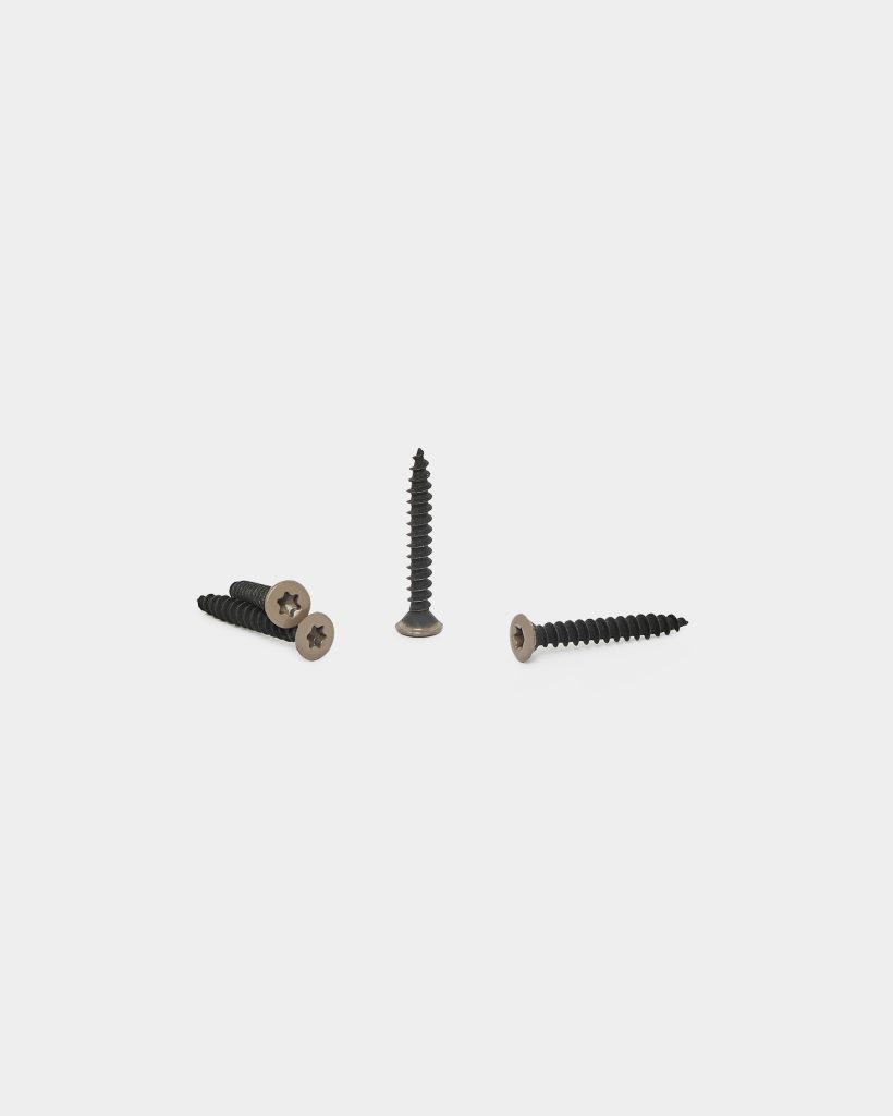White-background product photo for WoodUpp showing four WoodUpp wood screws: black, coarse-threaded shanks with bronze-toned countersunk heads and star/Torx drive. Three screws lie flat while one stands upright, illustrating length, tapered thread profile and flat head suitable for flush installation in timber.