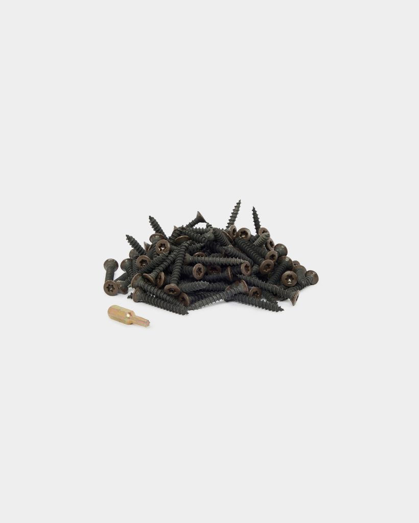 WoodUpp: a small pile of dark brown exterior wood screws with star (Torx) heads and tapered threads sits centered on a white background, accompanied by a single short gold-colored screwdriver bit. The WoodUpp screws appear coarse-threaded for decking or outdoor timber fastening.