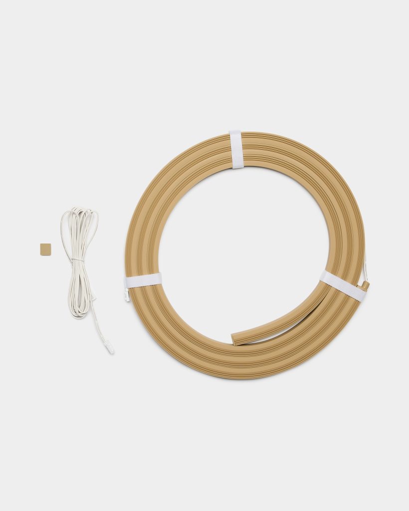 WoodUpp product image shows a coiled wood-effect flexible trim profile in light oak, secured with white straps, showing a grooved channel, alongside a long white WoodUpp connector cable with plug and a small square adhesive pad on a white background.