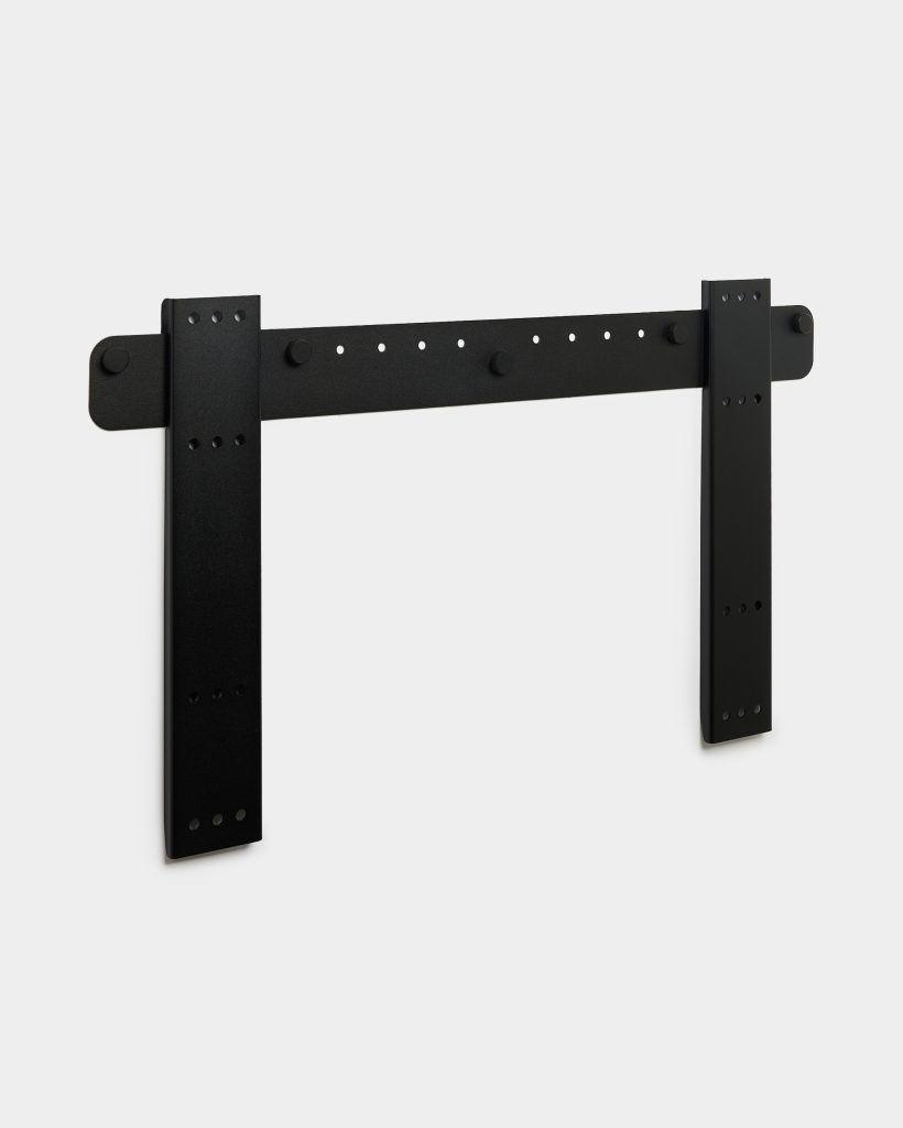 WoodUpp matte-black sliding door hardware: a wall-mounted steel rail with two vertical mounting straps and a horizontal bar featuring multiple pre-drilled holes and round stopper caps. Minimalist, powder-coated finish and sturdy bracket plates intended for mounting barn- or panel-style interior doors.