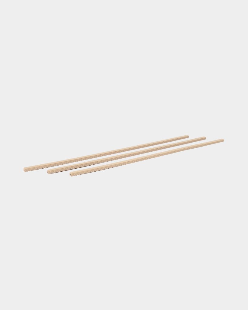 WoodUpp image showing three long, narrow, light pine wooden slats from WoodUpp, each with a shallow channel cut along one edge; the slats lie parallel and slightly staggered on a clean white background, highlighting the smooth, layered plywood grain and uniform rectangular profile.