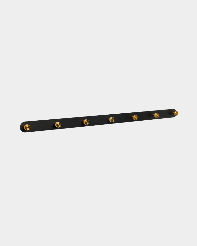 WoodUpp black wall-mounted peg rail with seven brass-finish round hooks arranged evenly along a slim matte black metal strip; minimalist coat rack ideal for coats, bags, and hats. Rounded ends and gold-tone pegs create a clean, modern industrial contrast for entryways and hallways.