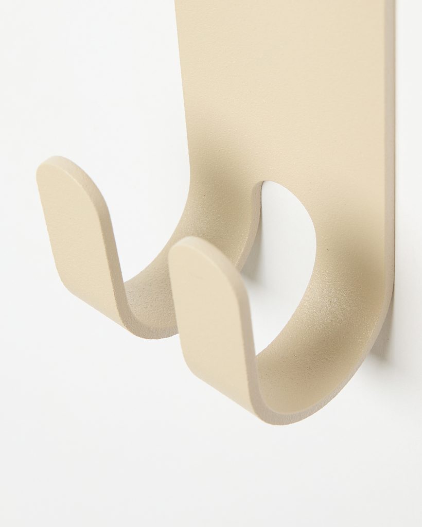 Close-up of a WoodUpp beige powder-coated metal double wall hook: a minimalist U-shaped twin-prong coat and accessory hook mounted on a slim rectangular backplate. Smooth matte finish, gently rounded edges and shallow curvature provide modern, space-saving storage for coats, towels or bags.