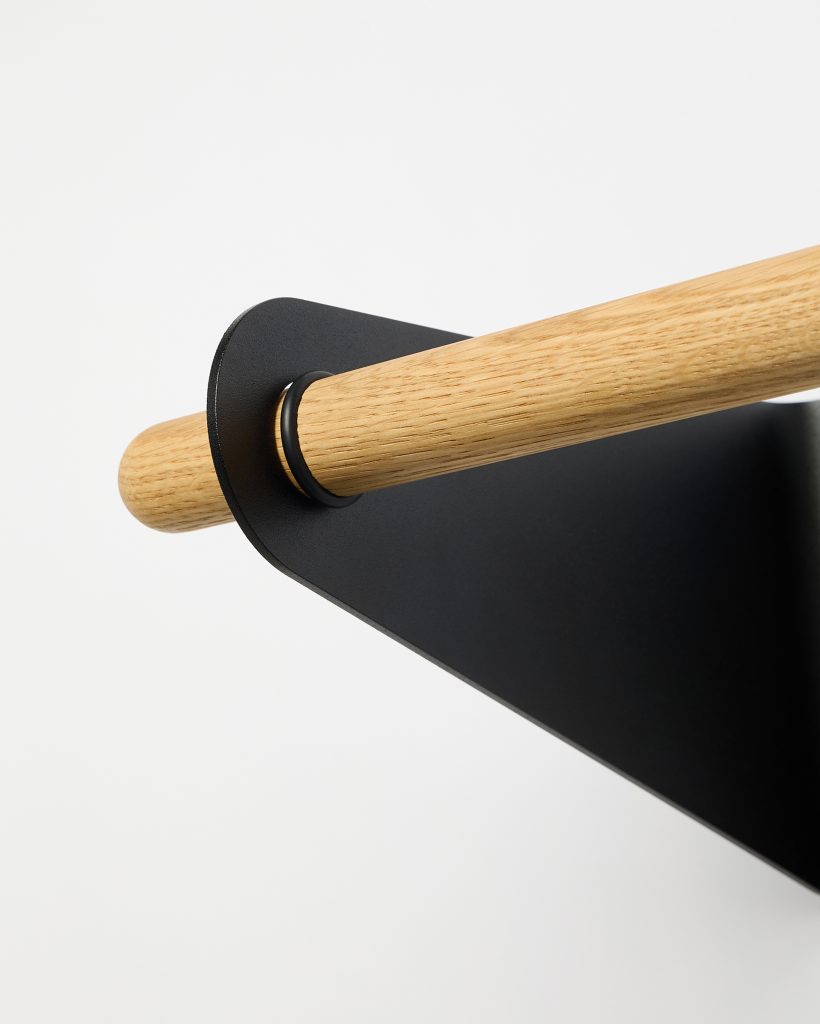 WoodUpp wall rail shown: a smooth natural oak dowel rod with visible grain threaded through a matte black powder‑coated steel bracket. The minimalist WoodUpp wooden rail and matching black metal wall bracket feature a rounded slot, black spacer ring, and clean Scandinavian-inspired design.
