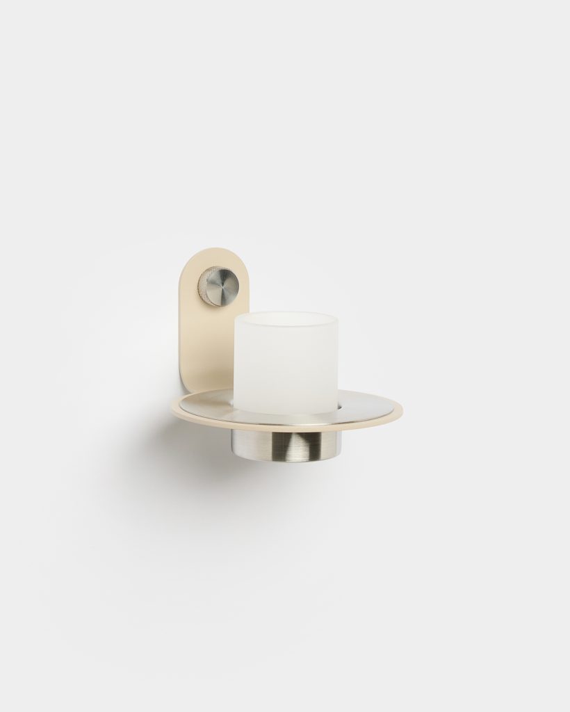 WoodUpp wall-mounted candle holder showcases a minimalist, elegant soft-cream metal bracket on a subtle rounded backplate, with a knurled stainless-steel adjustment knob, a circular brushed-steel tray and a frosted white glass candle cup centered on it, photographed against a plain white background.
